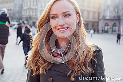 Beautiful blonde happy woman walking on the street in city. Outd