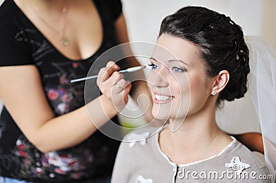 Beautiful bride applying wedding make-up by make-up artist