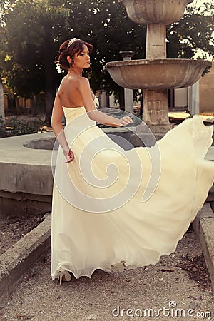Beautiful bride in elegant wedding dress posing at park