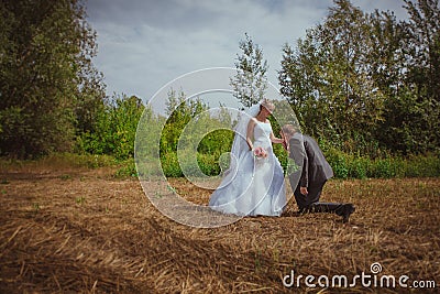 Beautiful bride and groom standing in grass and kissing. Wedding couple fashion shoot.
