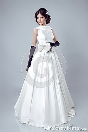 Beautiful bride woman posing in wedding dress isolated on gray b