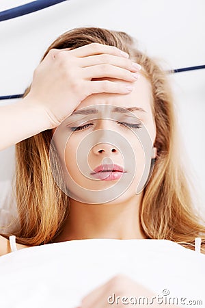 Beautiful casual caucasian woman lying in bed,touching her foreh