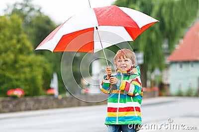 Beautiful child with yellow umbrella and colorful jacket outdoor