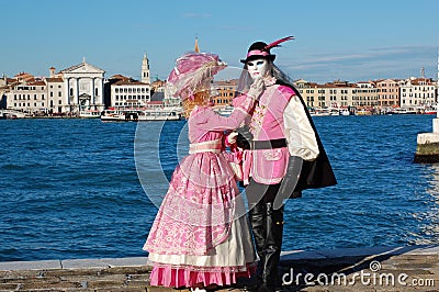 Beautiful couple in colorful costumes and masks, view on Piazza San Marco