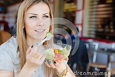 Beautiful elegant blond young woman eating salad in restaurant portrait image