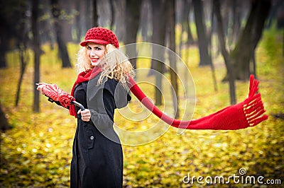 Beautiful fashionable young girl with red umbrella , red cap and red scarf in the park