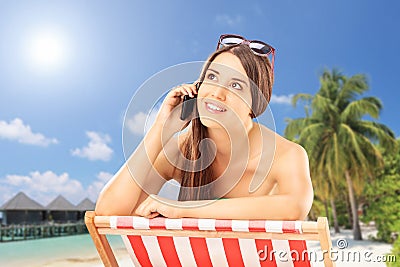 Beautiful female on a chair talking on a phone, on a beach