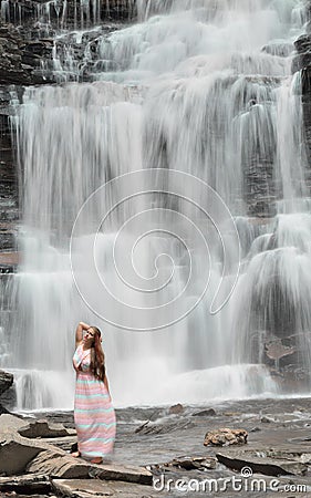 Beautiful female model posing in front of waterfall