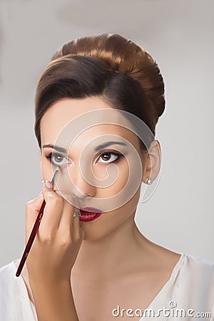Beautiful girl applying make-up by make-up artist