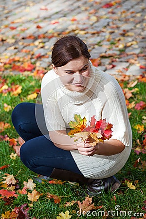 Beautiful girl in the autumn park collects leaves