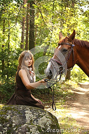 Beautiful girl and brown horse portrait in mysterious forest