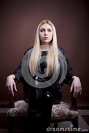 Beautiful girl in leather jacket on a vintage chair looking up