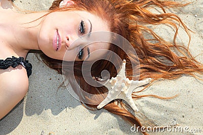 The beautiful girl lies on sea coast with shells nature vacation