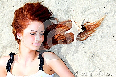 The beautiful girl lies on sea coast with shells nature vacation