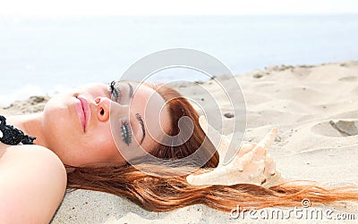 The beautiful girl lies on sea coast with shells nature vacation
