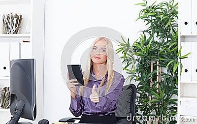 Beautiful girl at office at the computer with reader a thumb up