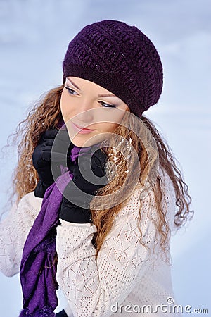 Beautiful girl in a purple knitted winter hat and scarf