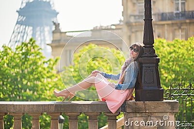 Beautiful girl sitting near the Eiffel tower