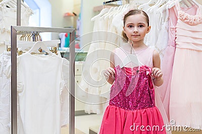 Beautiful girl tries on a festive red dress in the store