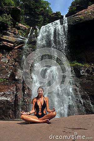 Beautiful girl wearing black one piece swimsuit meditating in lotus yoga pose