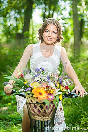 Beautiful girl wearing a nice white dress having fun in park with bicycle. Healthy outdoor lifestyle concept. Vintage scenery