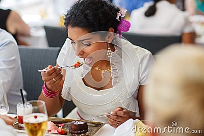 Beautiful happy indian bride eating on wedding dinner.