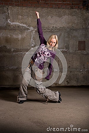 Beautiful hip-hop girl dancing over brick wall