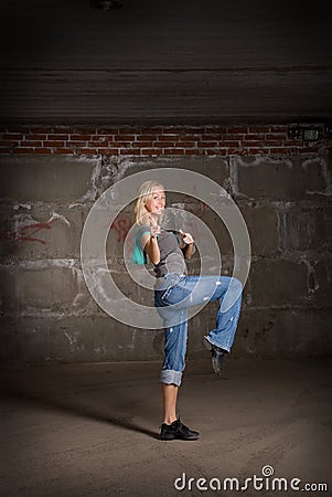 Beautiful hip hop girl dancing over brick wall