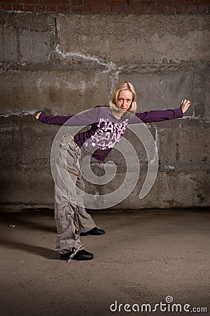 Beautiful hip hop girl dancing over grey brick wal