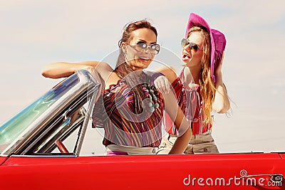 Beautiful ladies with sun glasses posing in a vintage car in a sunny day spring summer
