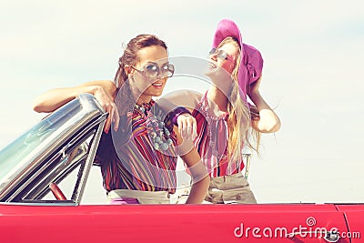 Beautiful ladies with sun glasses posing in a vintage retro car