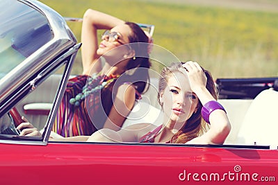 Beautiful ladies with sun glasses riding a vintage retro car
