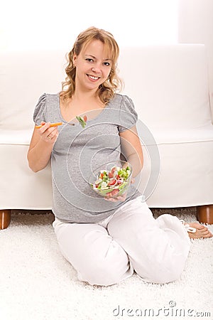 Beautiful pregnant woman eating salad