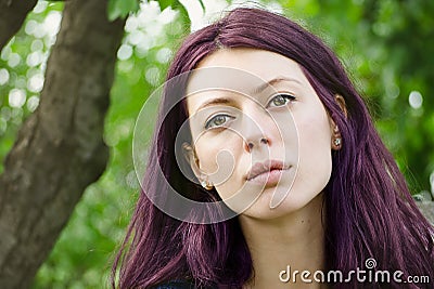 Beautiful purple haired girl looking serious on a green background
