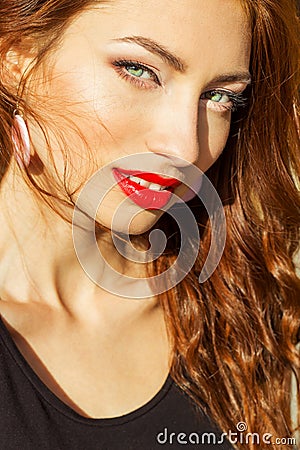 Beautiful sexy girl with red hair with big red lips with makeup in the city on a Sunny summer day