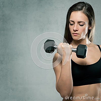 Beautiful sporty muscular woman with dumbbell