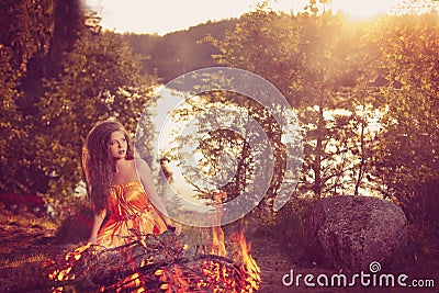 Beautiful witch in the woods near the fire. Magic woman celebrat
