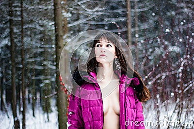 Beautiful woman with breast in pink coat in winter forest