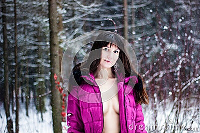 Beautiful woman with breast in pink coat in winter forest