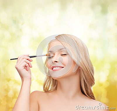 Beautiful woman with closed eyes and makeup brush