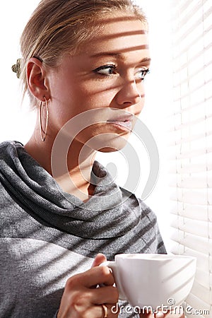 Beautiful woman with cup of coffee beside a window