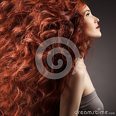 Beautiful woman with curly hair on gray background