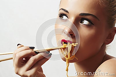 Beautiful woman are eating noodles.red lips.Chinese sticks. fast food