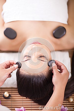 Beautiful woman having a wellness head massage with stones