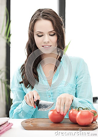 Beautiful woman in the kitchen cutting vegetables