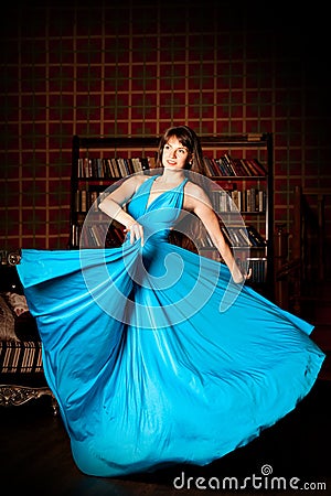 Beautiful woman in a long blue dress in the rich interior. Young