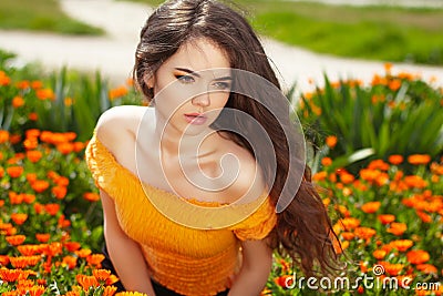 Beautiful woman with long brown hair over flowers field. Closeup