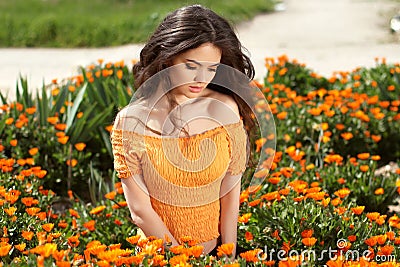 Beautiful woman with long brown hair over flowers field. Closeup
