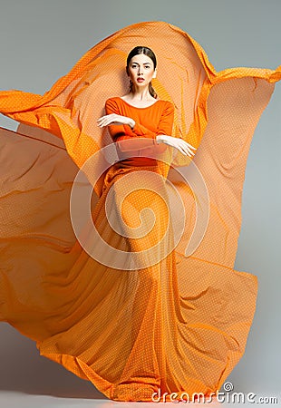 Beautiful woman in long orange dress posing dramatic