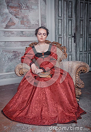 Beautiful woman in medieval dress on the armchair